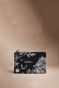 Une pochette noire à fermeture éclair avec des illustrations botaniques et architecturales blanches, le mot 