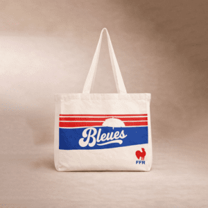 Sac fourre-tout beige à deux anses, avec des rayures rouges, un panneau bleu avec le mot 