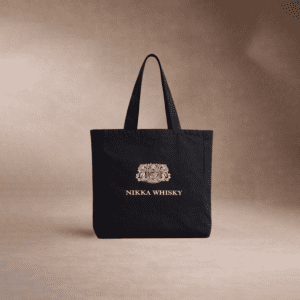 Un sac fourre-tout noir avec le logo et le nom Nikka Whisky imprimés en blanc sur un fond brun neutre.