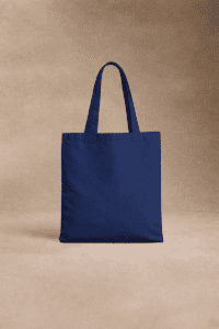 Un sac fourre-tout en tissu bleu marine uni avec deux poignées est présenté à la verticale sur un fond beige neutre.