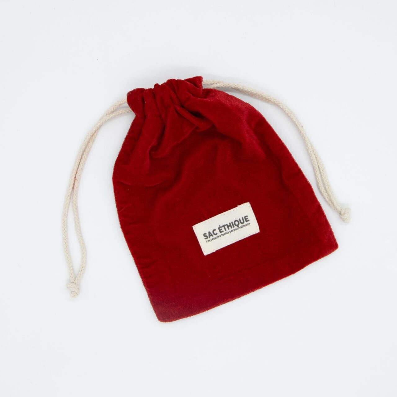 Un petit Pochon rouge épais couleur (280g/m2) de 15 x 10 cm avec des cordons blancs et une étiquette 