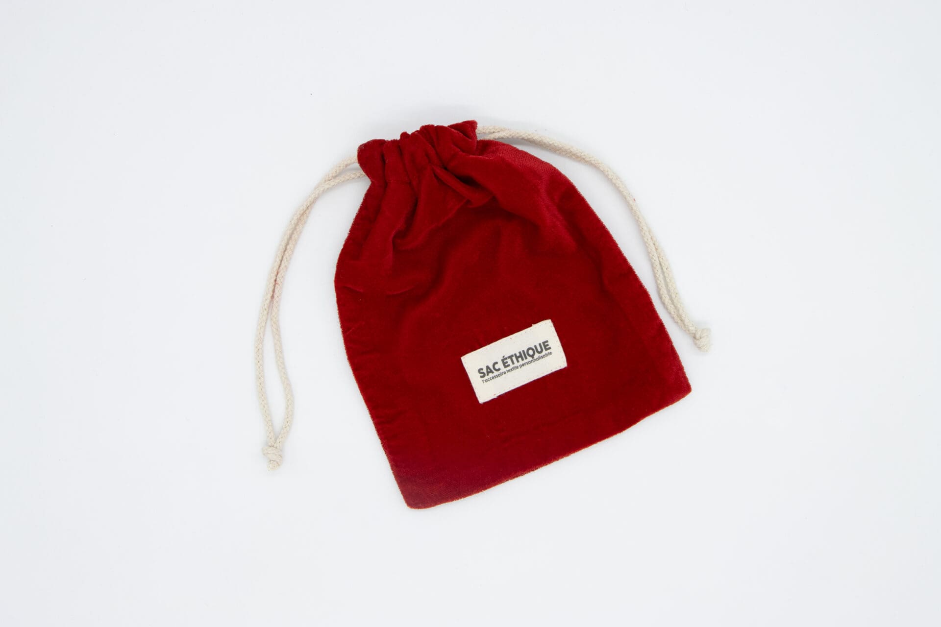 Un petit Pochon rouge épais couleur (280g/m2) de 15 x 10 cm avec des cordons blancs et une étiquette 